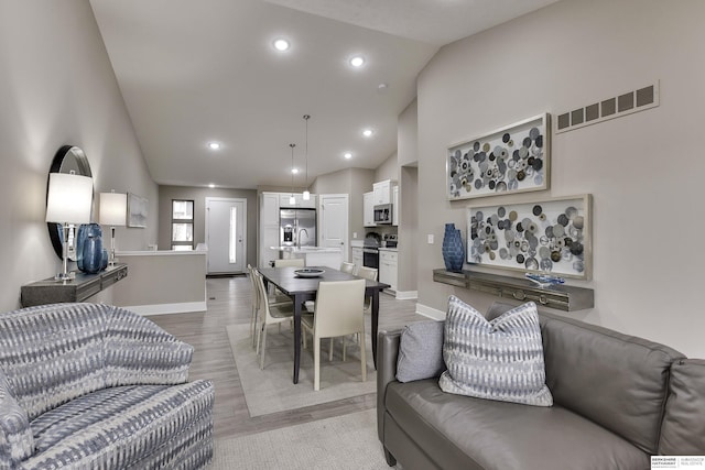 living room featuring sink, high vaulted ceiling, and light wood-type flooring