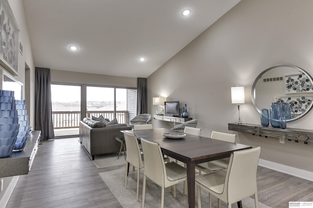 dining area with hardwood / wood-style floors and high vaulted ceiling