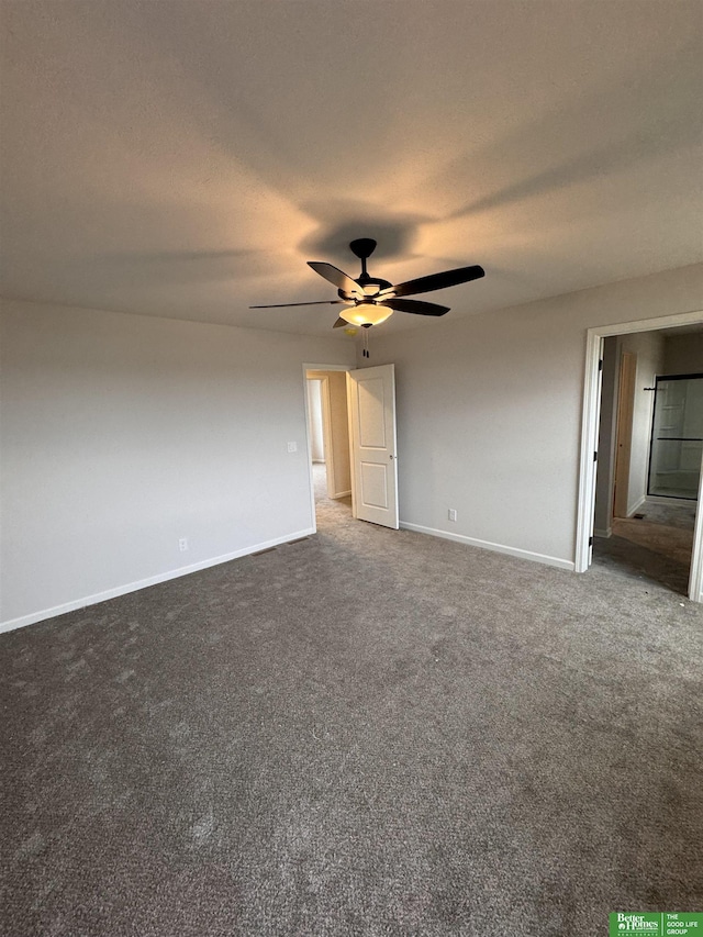 spare room featuring dark carpet and ceiling fan