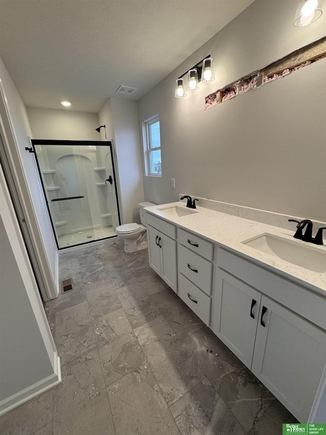 bathroom with vanity, a shower with shower door, and toilet