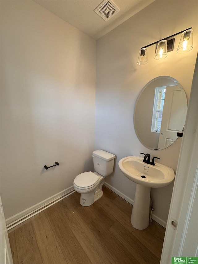 bathroom with a textured ceiling, hardwood / wood-style flooring, and toilet