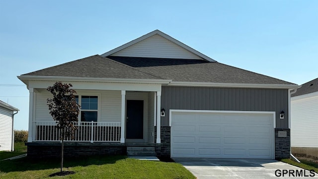 view of front of home featuring covered porch, a garage, and a front lawn