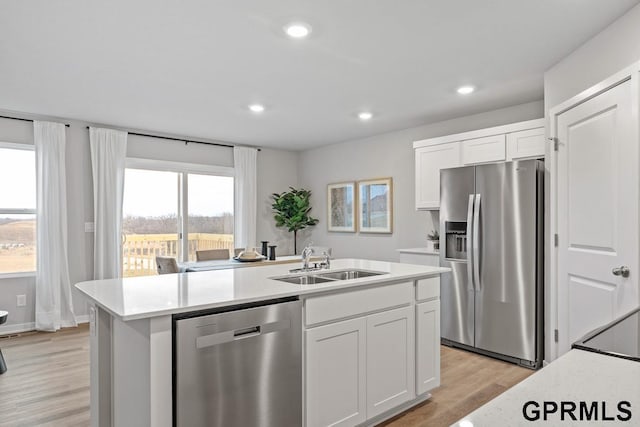 kitchen with white cabinetry, sink, an island with sink, light hardwood / wood-style floors, and appliances with stainless steel finishes