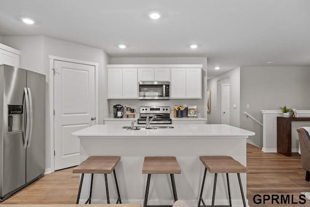 kitchen with a center island with sink, a kitchen bar, white cabinetry, and stainless steel appliances