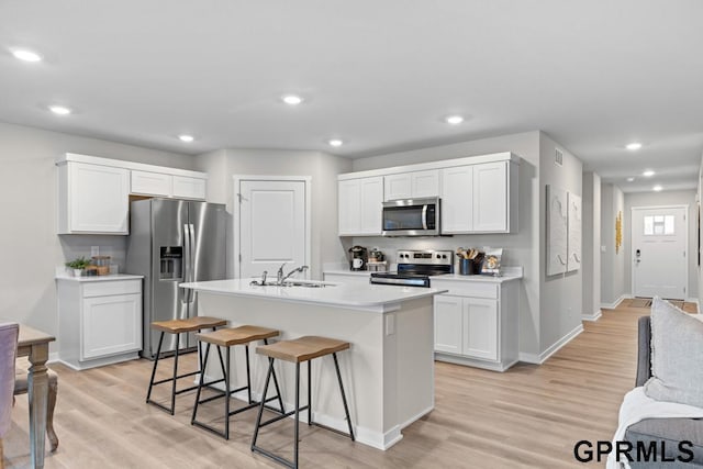 kitchen featuring white cabinets, a kitchen island with sink, appliances with stainless steel finishes, and light hardwood / wood-style flooring