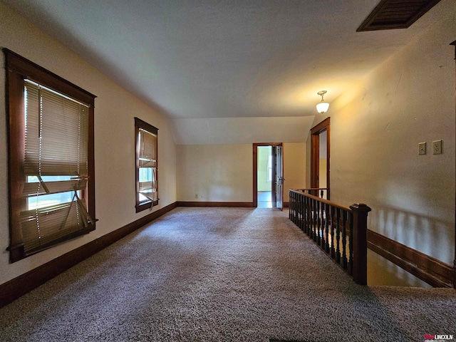 spare room with carpet flooring and vaulted ceiling