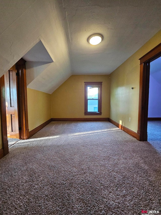 bonus room featuring vaulted ceiling, a textured ceiling, and carpet flooring