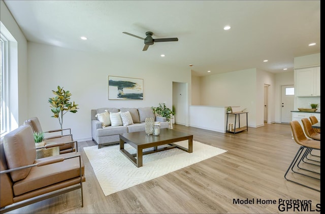 living room featuring baseboards, a ceiling fan, light wood-style flooring, and recessed lighting