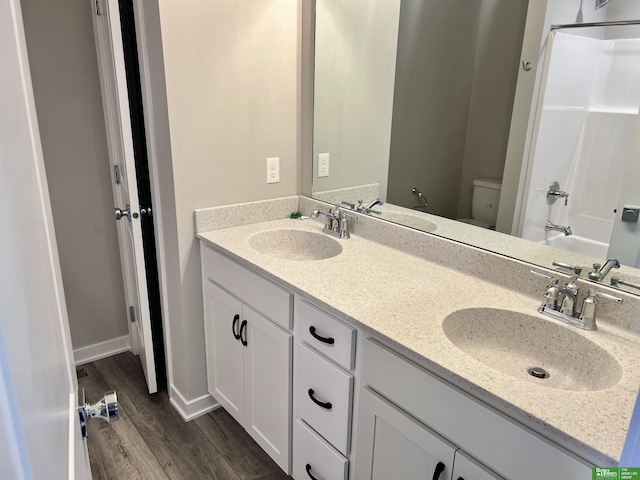 full bathroom with wood finished floors, double vanity, toilet, and bathing tub / shower combination