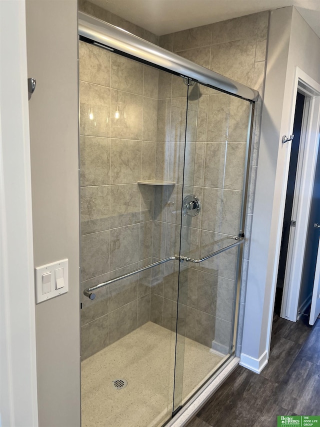 bathroom featuring a shower stall, wood finished floors, and baseboards