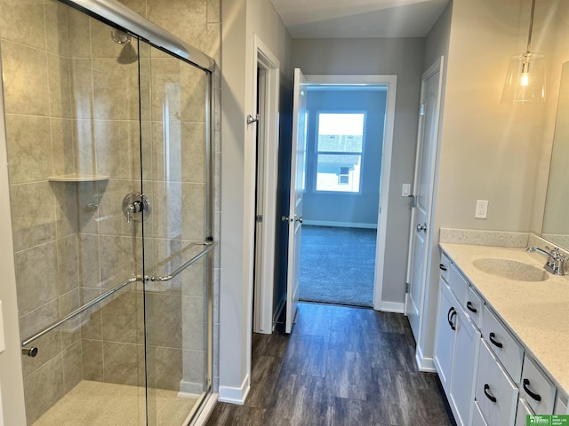 full bathroom featuring a shower stall, baseboards, vanity, and wood finished floors