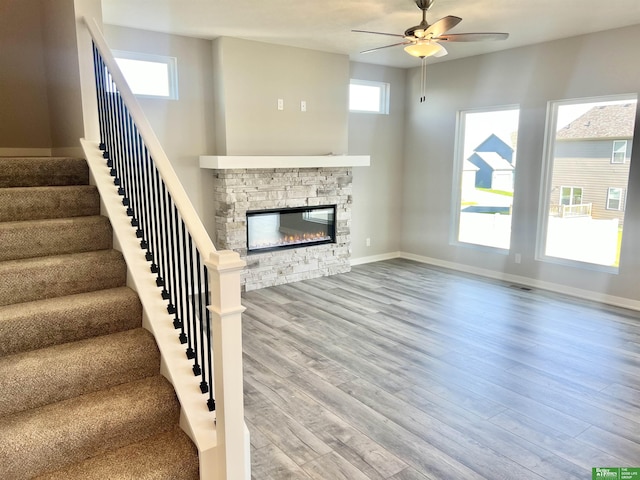unfurnished living room featuring ceiling fan, stairs, baseboards, and wood finished floors