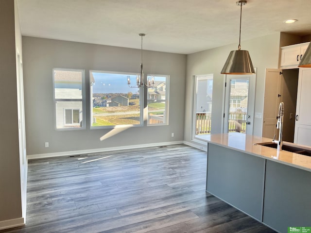 unfurnished dining area with a sink, dark wood-type flooring, baseboards, a chandelier, and recessed lighting