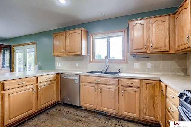 kitchen with tasteful backsplash, sink, kitchen peninsula, appliances with stainless steel finishes, and dark hardwood / wood-style flooring