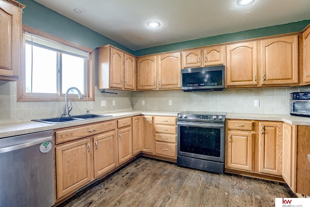 kitchen with appliances with stainless steel finishes, sink, dark wood-type flooring, and tasteful backsplash