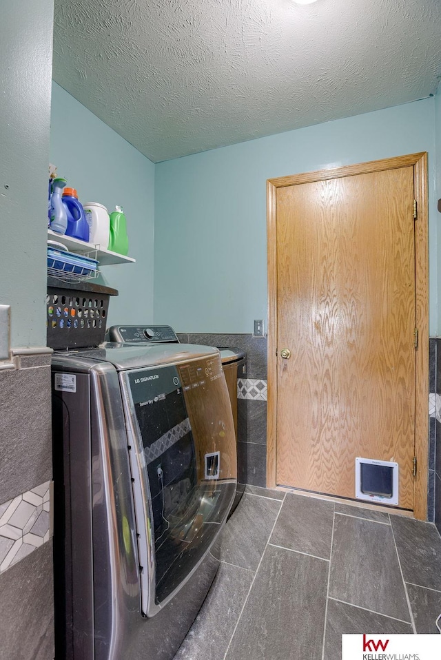 clothes washing area with a textured ceiling and washing machine and clothes dryer