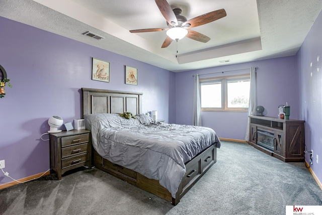 carpeted bedroom with a textured ceiling, a tray ceiling, and ceiling fan