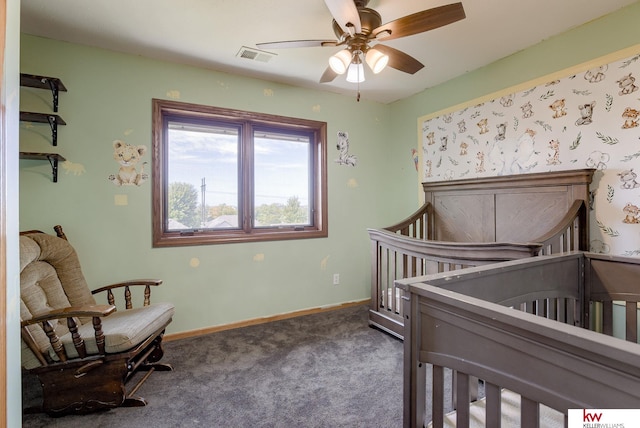 carpeted bedroom with a crib and ceiling fan