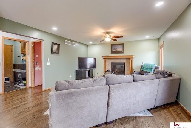 living room featuring a tiled fireplace, hardwood / wood-style floors, and ceiling fan