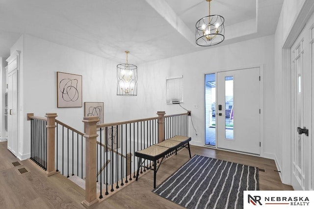 entryway featuring a tray ceiling, a chandelier, and dark hardwood / wood-style flooring