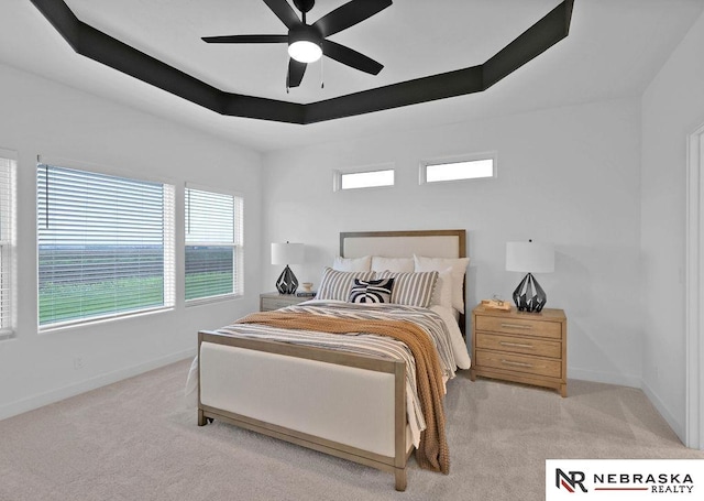 carpeted bedroom with ceiling fan and a raised ceiling