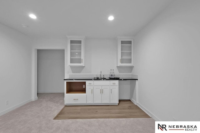 kitchen featuring sink, light colored carpet, and white cabinetry