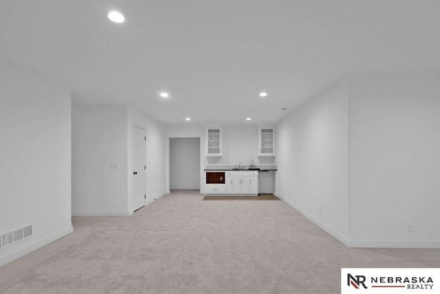 unfurnished living room with light carpet and sink