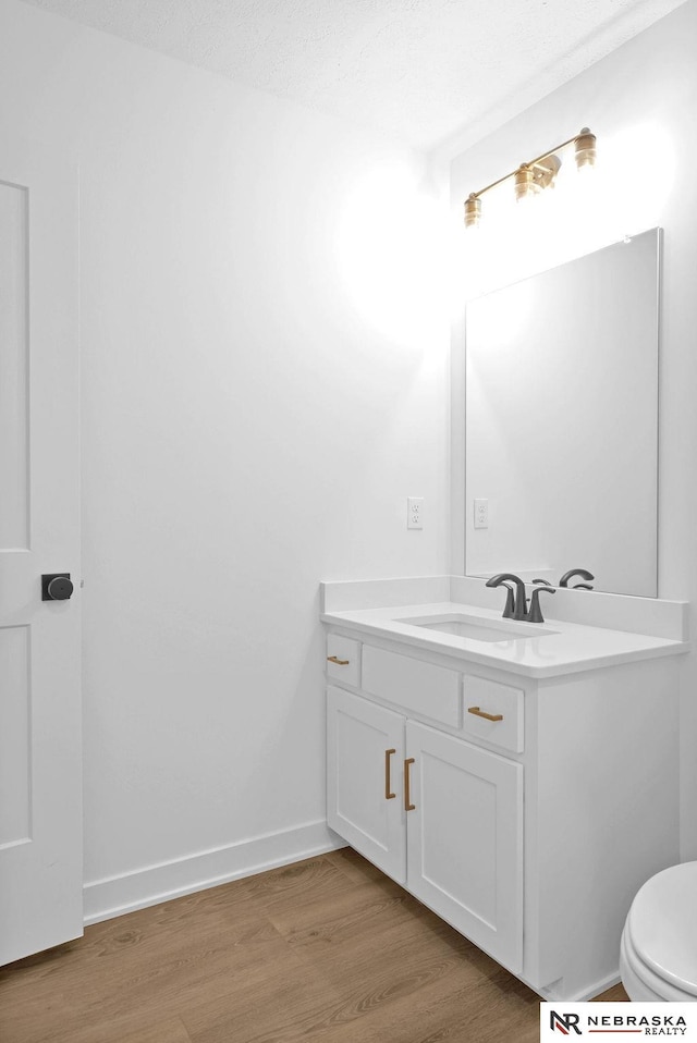 bathroom with toilet, vanity, and hardwood / wood-style flooring