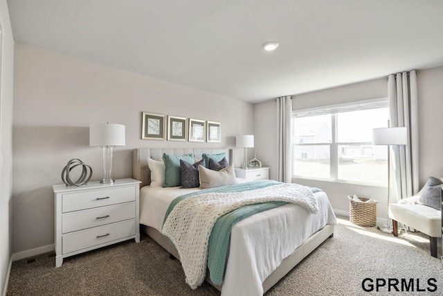 bedroom with dark colored carpet and baseboards