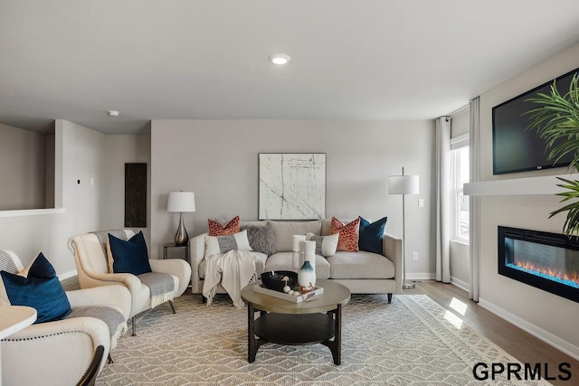 living room with a glass covered fireplace, light wood-style flooring, baseboards, and recessed lighting