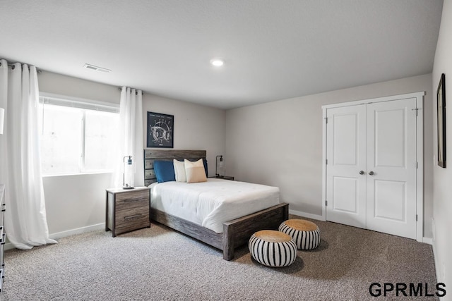 carpeted bedroom with a closet, visible vents, and baseboards