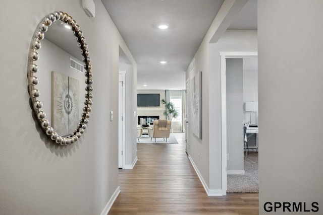 hallway with recessed lighting, wood finished floors, visible vents, and baseboards