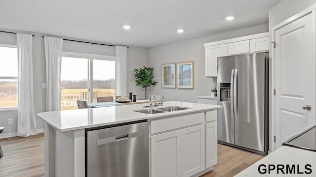 kitchen with sink, white cabinetry, light wood-type flooring, an island with sink, and stainless steel appliances