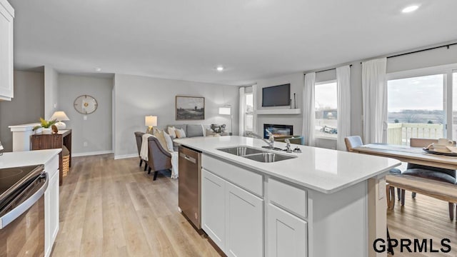 kitchen with white cabinetry, an island with sink, sink, stainless steel dishwasher, and electric range