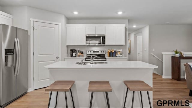 kitchen with white cabinetry, a center island with sink, a breakfast bar, and appliances with stainless steel finishes