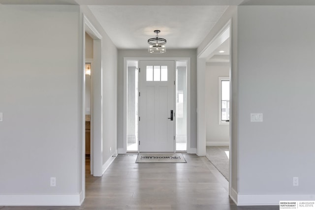 entrance foyer featuring a notable chandelier, light hardwood / wood-style flooring, and a healthy amount of sunlight