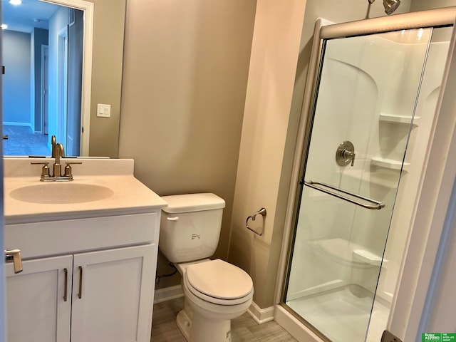 bathroom featuring toilet, a shower with door, and vanity