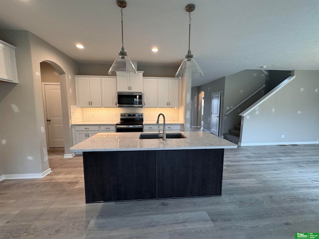 kitchen featuring a kitchen island with sink, sink, white cabinets, and appliances with stainless steel finishes