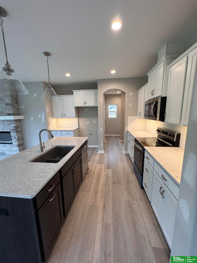 kitchen featuring sink, stainless steel appliances, light hardwood / wood-style flooring, decorative light fixtures, and white cabinets