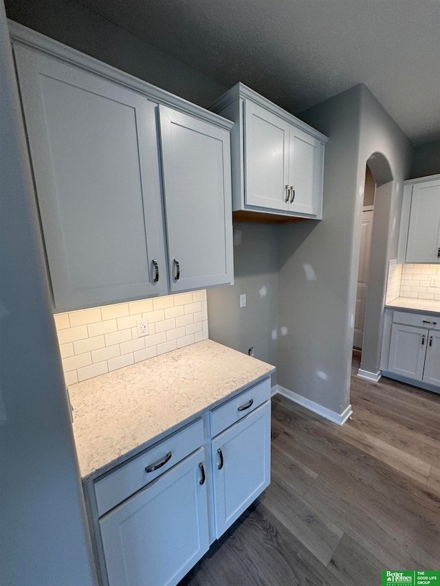 kitchen with white cabinets, decorative backsplash, dark wood-type flooring, and a textured ceiling