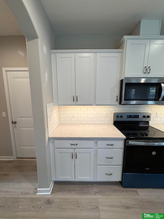 kitchen featuring decorative backsplash, white cabinetry, and stainless steel appliances