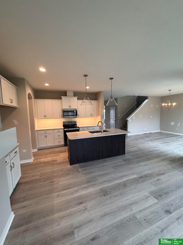 kitchen featuring range with electric stovetop, white cabinetry, sink, and a kitchen island with sink