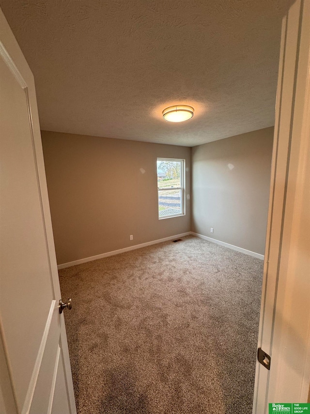 carpeted empty room with a textured ceiling