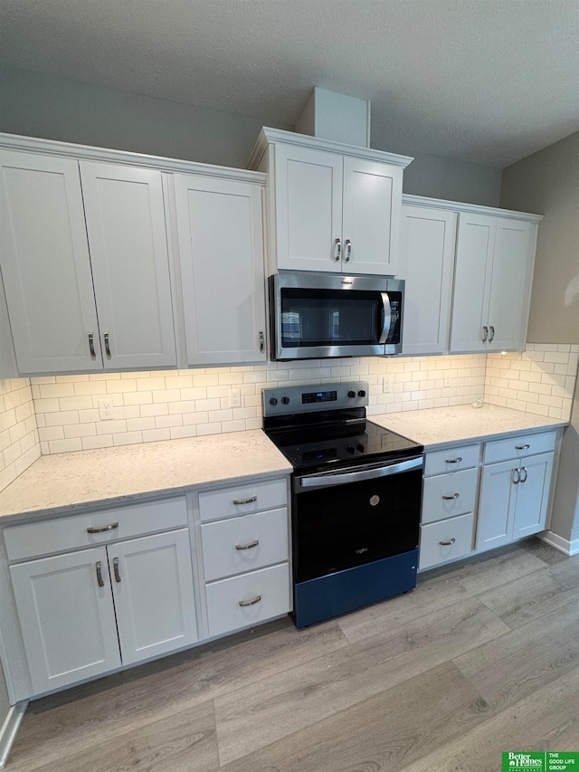 kitchen featuring decorative backsplash, light wood-type flooring, stainless steel appliances, and white cabinetry