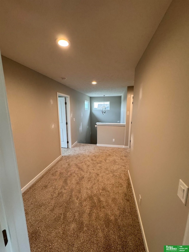 hall with carpet flooring and an inviting chandelier