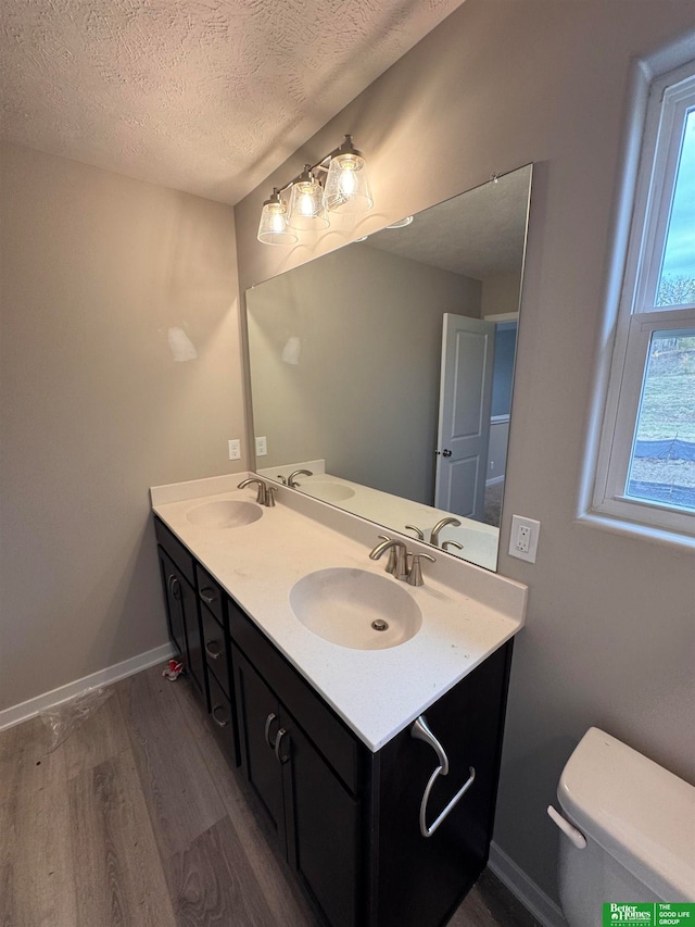 bathroom featuring a wealth of natural light, wood-type flooring, a textured ceiling, and toilet