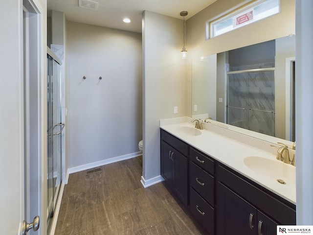 bathroom featuring vanity, hardwood / wood-style flooring, toilet, and a shower with shower door