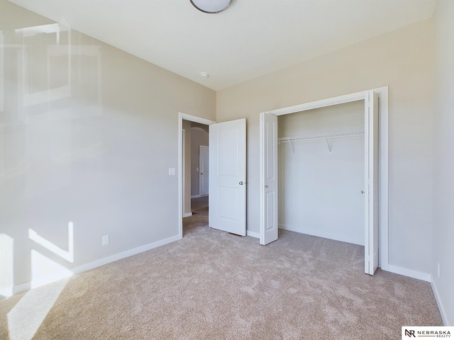 unfurnished bedroom featuring light colored carpet and a closet