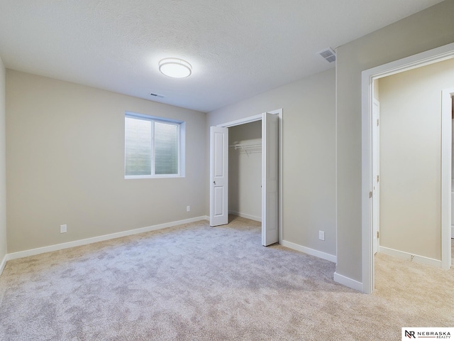 unfurnished bedroom featuring a closet, light colored carpet, and a textured ceiling