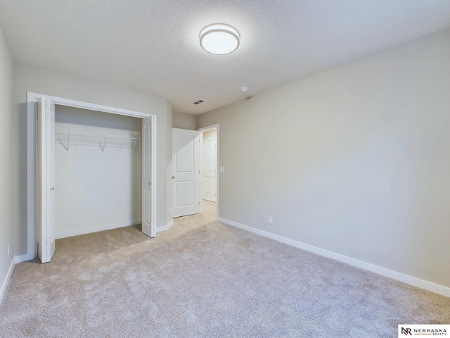 unfurnished bedroom with a textured ceiling, light colored carpet, and a closet